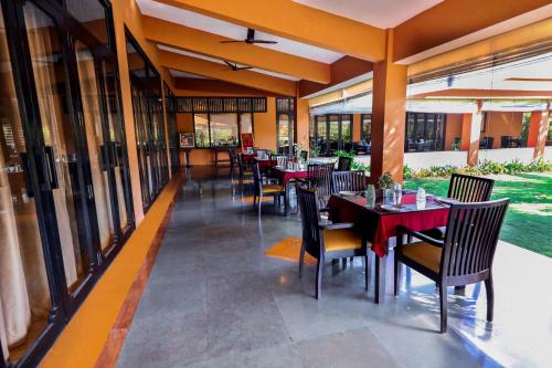 甘帕普拉Blue Ocean The Fern Resort & Spa Ganpatipule的餐厅设有桌椅和窗户。
