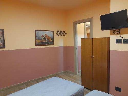 迪亚诺马里纳Albergo Jolanda的客房设有一间墙壁上配有电视的卧室。