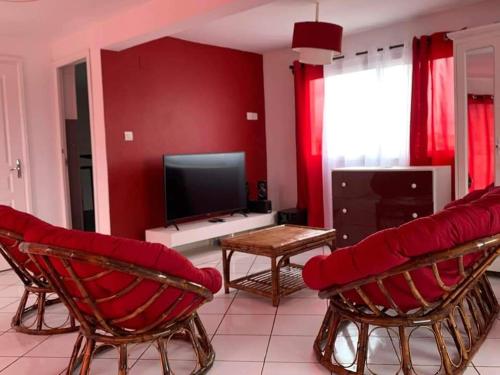 塔那那利佛Appartements Andrian Location的客厅设有红色的墙壁和椅子,配有电视