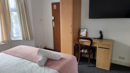 桑当Fair Oak Self-Catering Accomodation的一间卧室配有一张床和一张书桌及电视