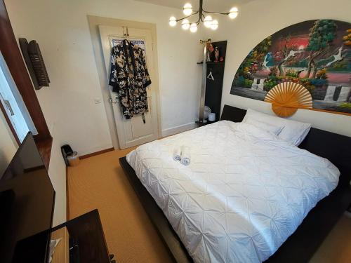 Bed and Breakfast Lek & Jo的卧室配有白色的床和墙上的绘画作品