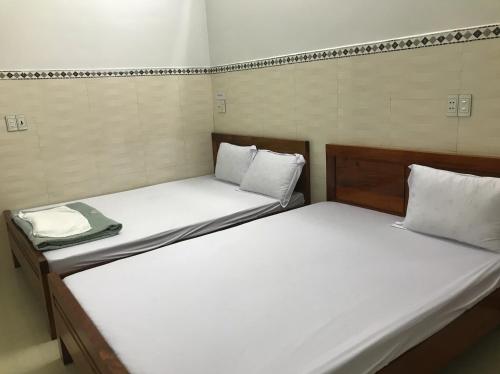 Quang TriNhà nghỉ Bình An - Binh An Motel的小客房内的两张床,配有白色床单