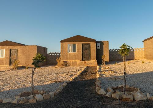 达纳Dana Sunset Eco Camp的沙漠中一座建筑物前面的两棵树