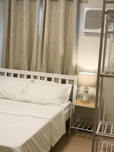 杜马格特2BR Cozy Seaside Condo in Dumaguete的一间卧室设有两张床和一张桌子上的台灯。