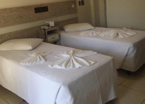 伊瓜苏Hotel AVM的配有白色床单的酒店客房内的两张床