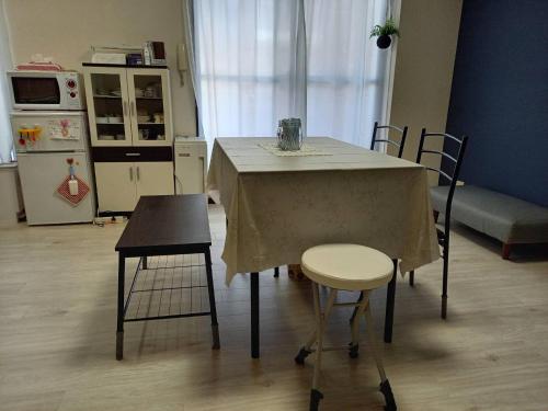 福冈FukuokaKoryou GuestHouse的厨房配有带2把椅子的桌子和冰箱。