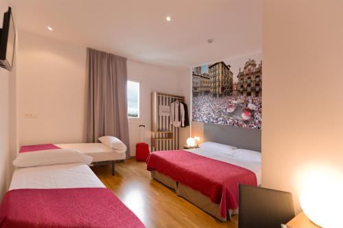 潘普洛纳IRAIPE Pamplona Hostal的酒店客房,配有两张带红色床单的床