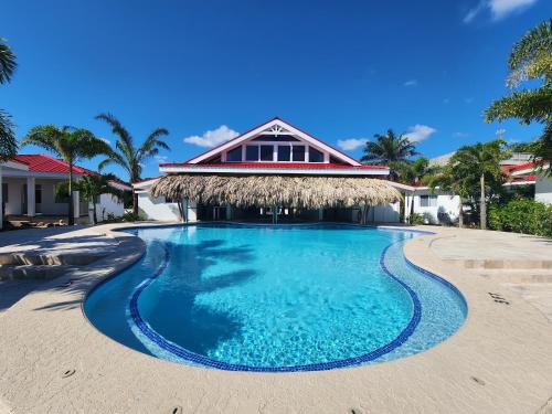 玛雅湾Ceiba Beach Resort的一座位于带茅草屋顶的度假村前方的游泳池