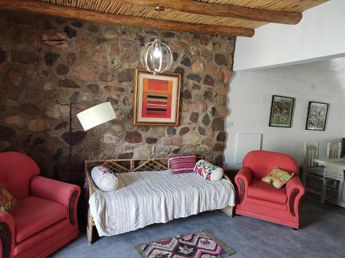 胡阿卡勒拉El Cobijo del Artista - en Huacalera的一间卧室配有一张床和两张红色椅子