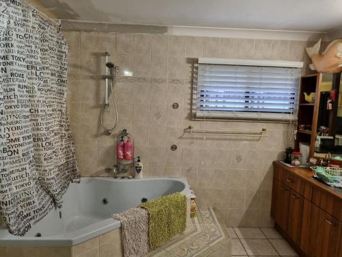 凯恩斯朱莉的民宿的带浴缸的浴室和窗户。