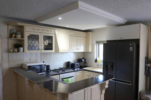 格莱内尔格Sunsets At Glenelg的厨房配有白色橱柜和黑色冰箱。