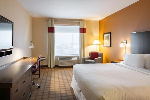 尼斯库温尼伯国际机场福朋喜来登酒店 的配有一张床、一张书桌和一扇窗户的酒店客房