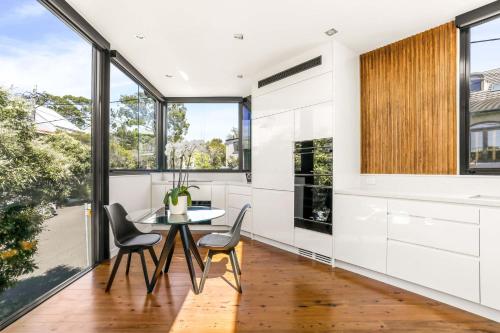 悉尼Woollahra house beautiful 3 bedroom terrace的厨房配有桌椅和大窗户。