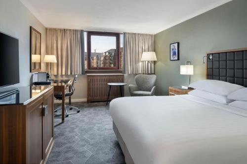 斯旺西Delta Hotels by Marriott Swansea的酒店客房配有一张床、一张书桌和一台电视。