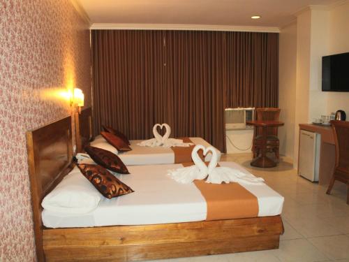 马尼拉Rosas Garden Hotel的两张床铺,位于酒店客房内,配有天鹅
