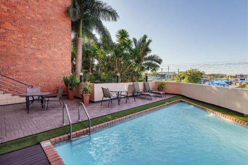 卢萨卡卢萨卡普罗蒂亚酒店的庭院内的游泳池,配有桌椅