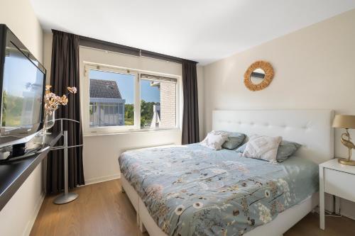 布勒克伦Luxury Apartment near Utrecht & Amsterdam的一间卧室设有一张床、一台电视和一个窗口。
