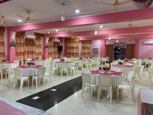 马纳尔Hotel Juli Reception的宴会厅配有白色的桌椅和粉红色的墙壁