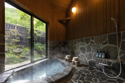 由布市汤布院茶寮日式旅馆的带浴缸和窗户的大浴室
