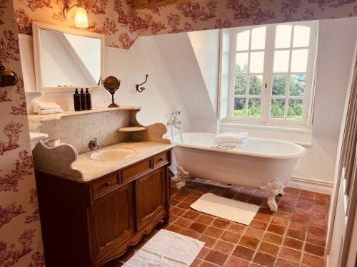 普瓦维莱特城堡酒店的带浴缸、水槽和窗户的浴室