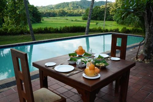 RidigamaRaddegoda Walawwa Kurunegala的一张木桌,旁边是游泳池,上面有食物