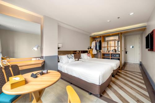 曼谷Vince Hotel Pratunam的配有一张床、一张桌子和一张桌子的酒店客房
