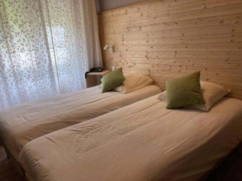 克吕特法国奥贝格酒店的一间卧室配有两张床,提供白色的床单和绿色的枕头