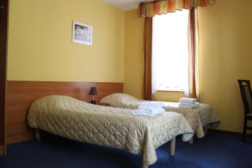 图霍拉Hotel Pod Jeleniem的酒店客房设有两张床和窗户。