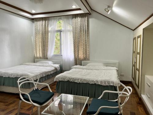 碧瑶CAMPJOHNHAY Forest Estate的配有两张床铺的玻璃桌和椅子