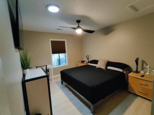 海波因特Modern/Retro Condo的一间卧室配有黑色的床和吊扇