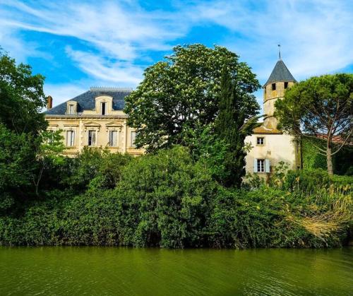 特雷布Château sur le Canal du midi proche de Carcassonne的一座大建筑,位于河边