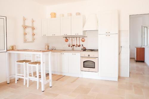 奥斯图尼Villa Mina的白色的厨房配有白色的橱柜和桌子