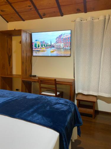 帕拉蒂Pousada Antígona的卧室配有一张床,墙上配有电视。