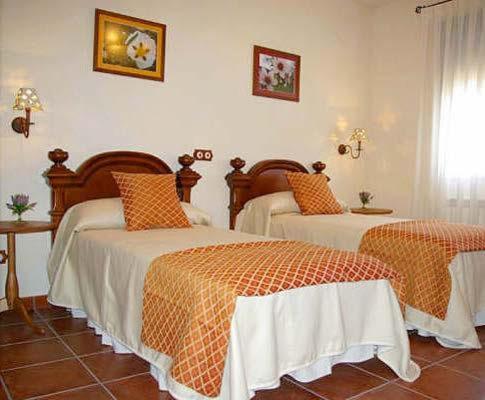 San Pablo de los MontesCasa Rural Cristina I的一间卧室配有两张带橙色和白色床单的床