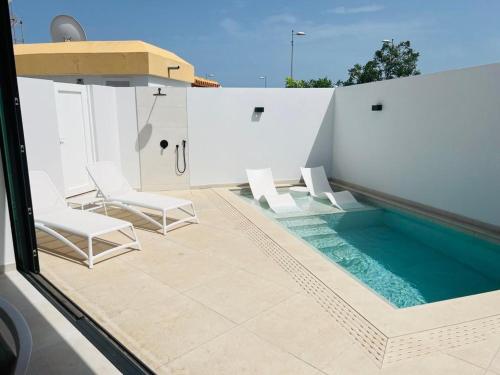 马斯帕洛马斯Villa Siena, in the center of Playa del Ingles, close to CC Jumbo的一个带椅子的庭院和一个游泳池