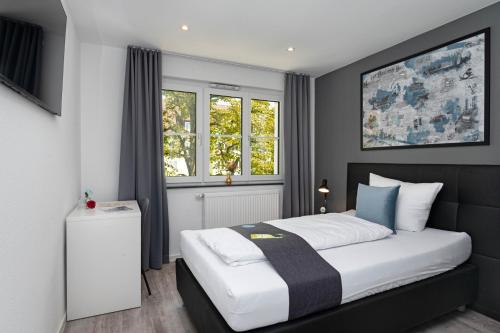 SpaichingenHotel Das Q Spaichingen的一间卧室设有一张床和两个窗户。