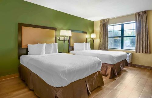 兰辛Sonesta Simply Suites Lansing的酒店客房设有两张床和窗户。