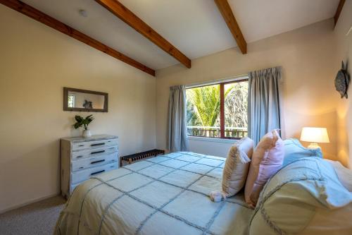 欧尼坦基Onetangi Beach Retreat - Waiheke Holiday Home的一间卧室设有一张大床和一个窗户。