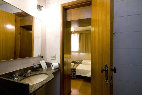 里约热内卢朗多尼亚皇宫酒店的一间带水槽和镜子的浴室以及一张床