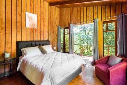 蒙泰韦尔德哥斯达黎加Wildlife Refuge’s Wood Cabin的卧室配有床、椅子和窗户。