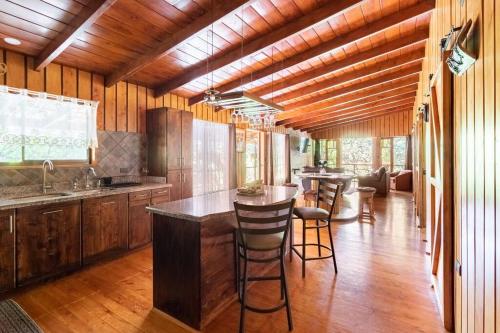 蒙泰韦尔德哥斯达黎加Wildlife Refuge’s Wood Cabin的铺有木地板的厨房和带凳子的酒吧