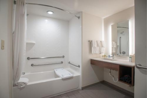 彭萨科拉彭萨科拉大学区假日酒店的白色的浴室设有浴缸和水槽。