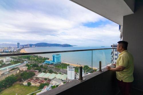 归仁FLC Sea Tower Quy Nhơn - Homostay的站在一个眺望着大海的阳台上的人