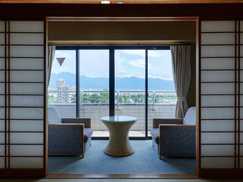 笛吹市Tabist Onsen Hotel Toyo的客房设有带桌椅的大窗户。