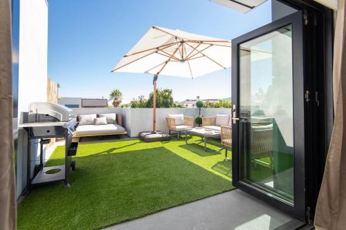 洛杉矶Regency Modern Apartments的一个带雨伞和绿草的庭院