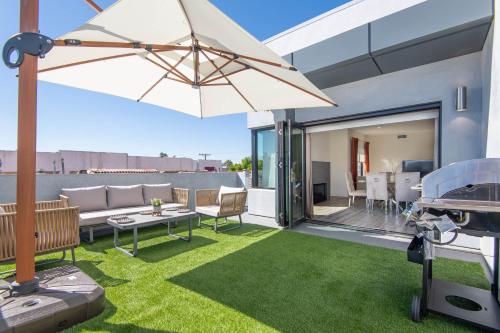 洛杉矶Regency Modern Apartments的一个带沙发和遮阳伞的庭院