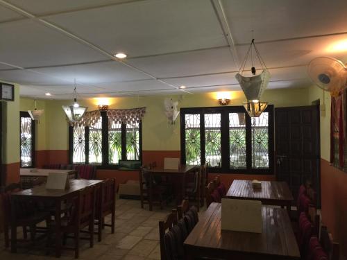 索拉哈潮塔里花园度假村的餐厅设有木桌、椅子和窗户。