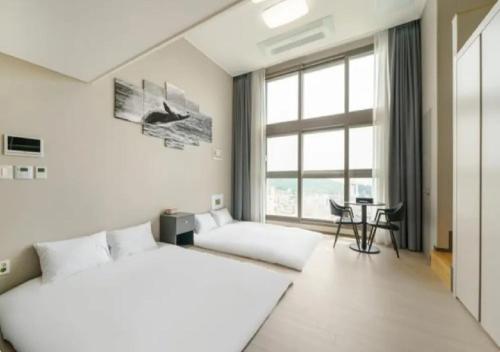 丽水市Coopstay Yeosu Hotel的一间卧室设有两张床、一张桌子和一个窗口。