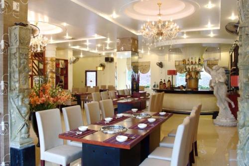 Thái BìnhKhách Sạn Kim Cương Thái Bình的一间带木桌和白色椅子的用餐室