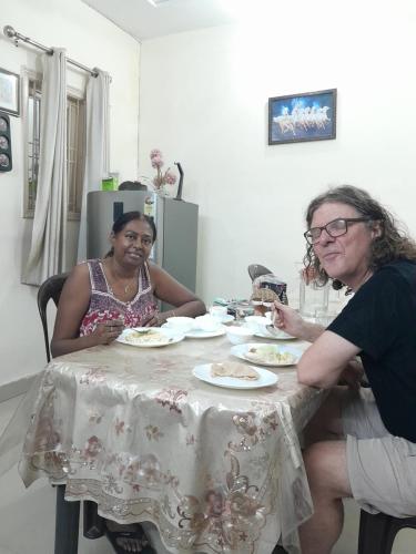 新德里Bhagvati BnB Homestay Apt的两个坐在餐桌上,配上食物盘的女人